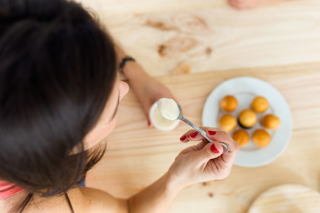 Free photo beautiful young woman eating yogurt at home.