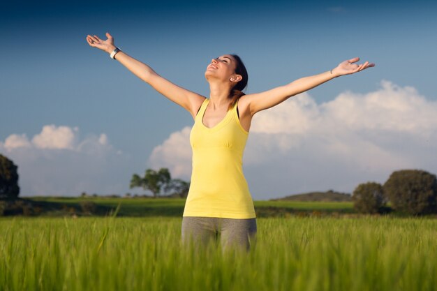 Beautiful young woman enjoying the spring standing in a cereal field