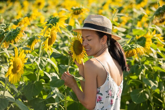 Beautiful young woman in a field of sunflowers in a white dress. travel on the weekend concept. portrait of authentic woman in straw hat . Outdoors on the sunflower field.