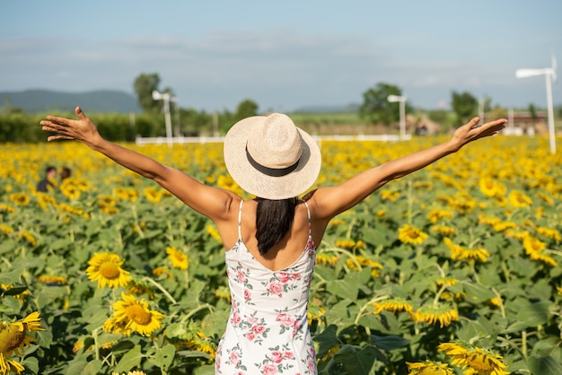 Bella giovane donna in un campo di girasoli in abito bianco. viaggiare sul concetto di fine settimana. ritratto di donna autentica in cappello di paglia. all'aperto sul campo di girasoli.