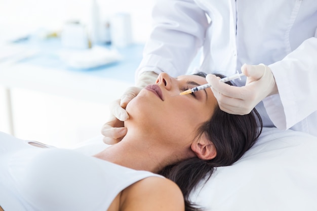 Beautiful young woman getting botox cosmetic injection in her face.