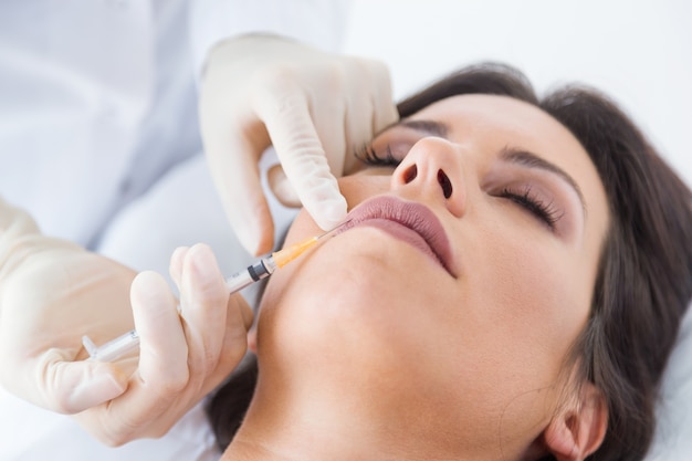 Beautiful young woman getting botox cosmetic injection in her face.