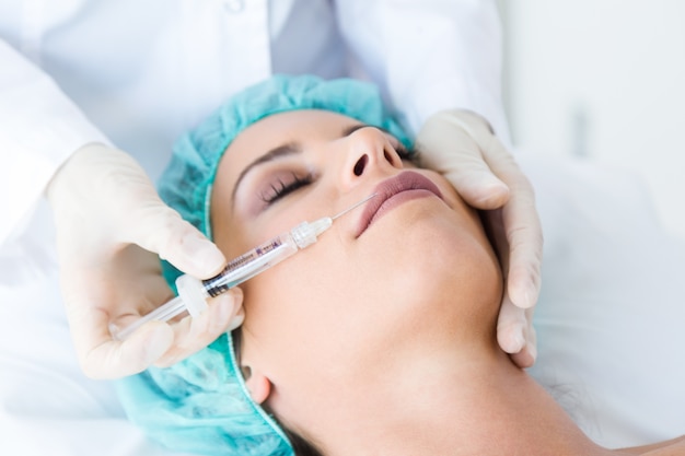 Beautiful young woman getting botox cosmetic injection in her face.