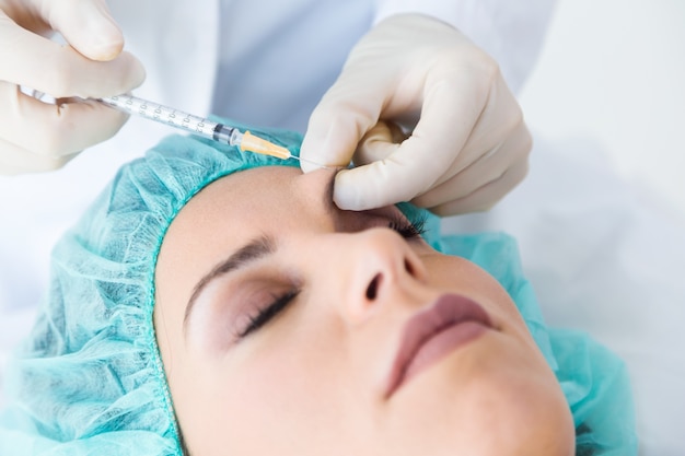 Beautiful young woman getting botox cosmetic injection in her face.