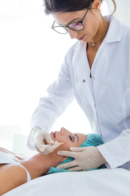 Beautiful young woman getting botox cosmetic injection in her face.