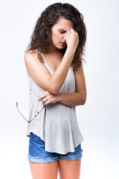 Beautiful young woman having headache over white background.