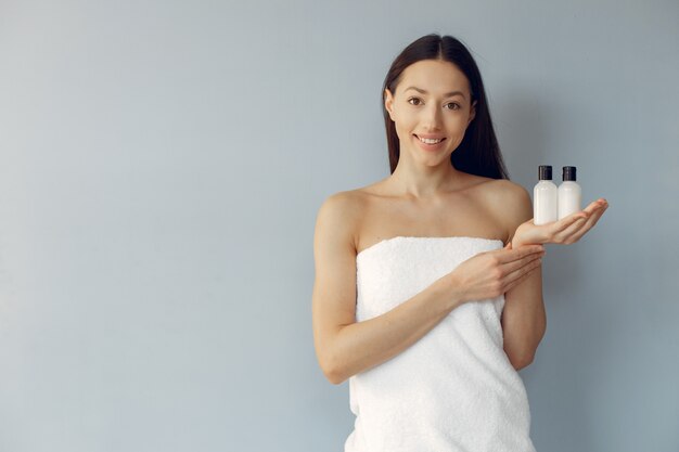 Beautiful young woman holding cream bottles