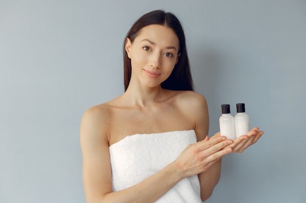 Beautiful young woman holding cream bottles