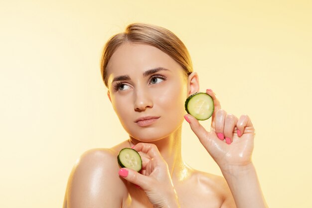 Beautiful young woman holding cucumber slices