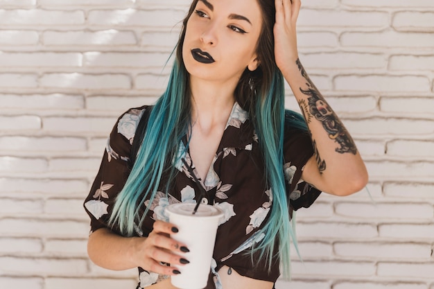 Beautiful young woman holding disposable coffee cup