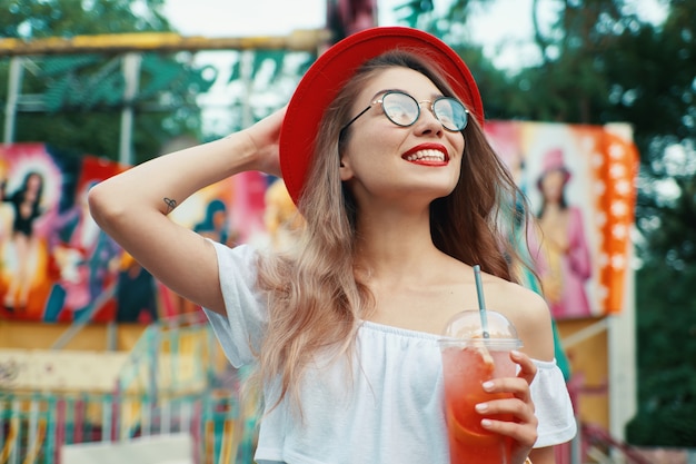 Foto gratuita bella giovane donna che tiene un drink mentre sorridendo