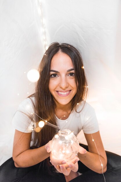 Beautiful young woman holding glowing sphere with ferry lights on her head