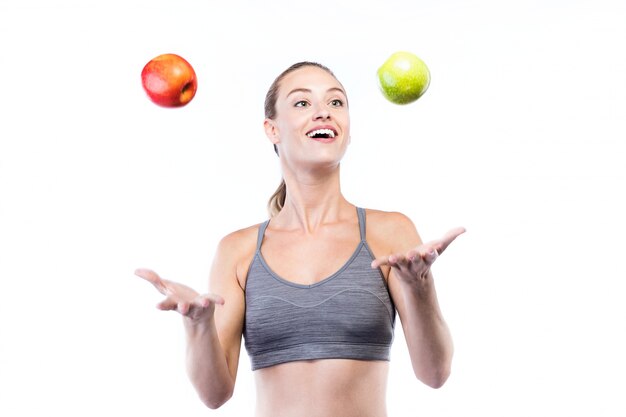 Beautiful young woman holding green and red apples over white background.