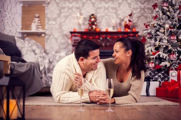 Beautiful young woman holding hands and giving affection to her boyfriend on christmas day. Couple having a drink.