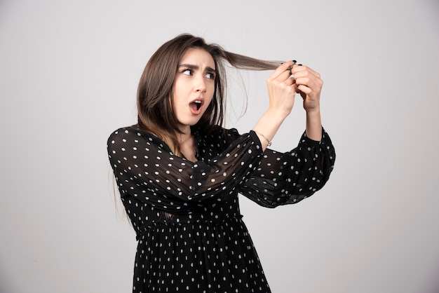 A beautiful young woman holding her healthy and shiny hair.