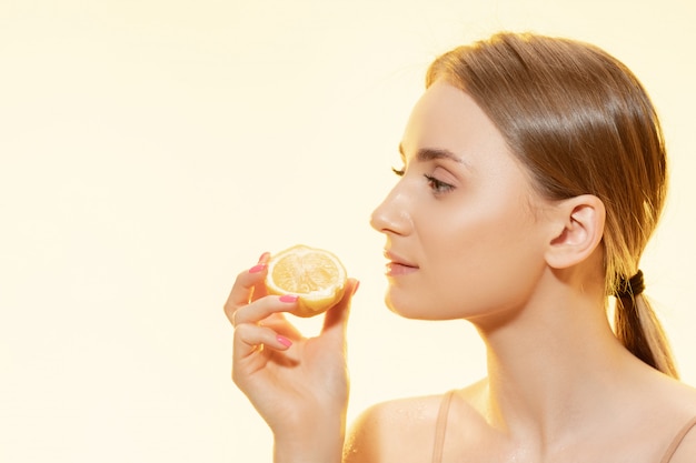 Beautiful young woman holding lemon slice