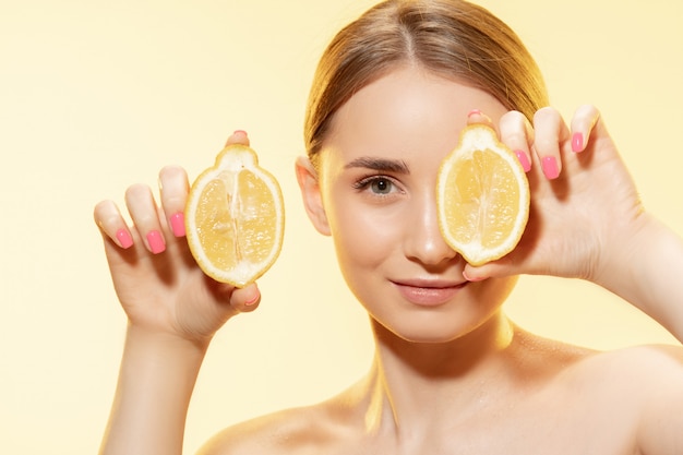 Красивая молодая женщина, держащая ломтики лимона