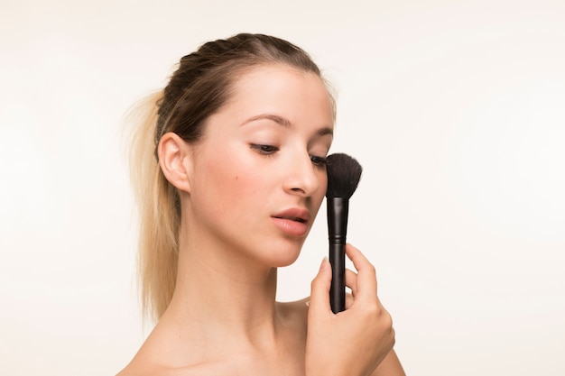 Beautiful young woman holding makeup brush