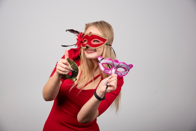 Beautiful young woman holding mysterious venetian masks.