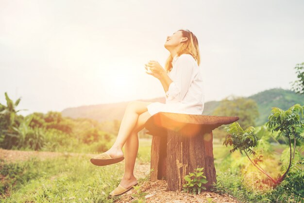 Beautiful young woman holding up a cup of coffee sitting on the