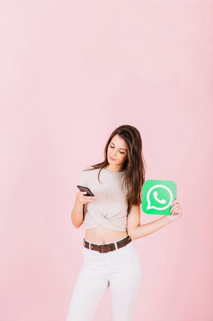 Beautiful young woman holding whatsapp icon using mobile phone