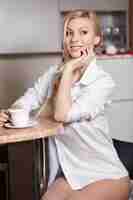 Free photo beautiful young woman holds a cup of coffe on kitchen