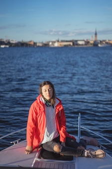 빨간 우비에 아름 다운 젊은 여자는 개인 요트를 탄다. 스톡홀름, 스웨덴
