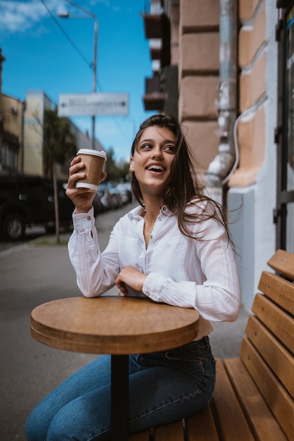 ストリートカフェの美しい若い女性はコーヒーを飲む