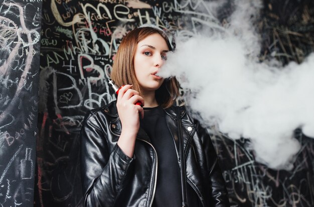 Beautiful young woman inhaling smoke. young girl vaping 
