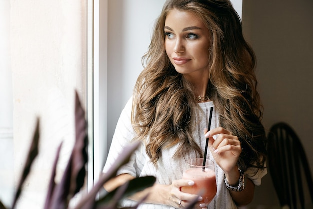 A beautiful young woman is posing in a cafe