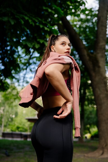 Beautiful young woman is resting after jogging in the park.