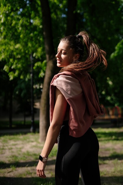 Beautiful young woman is resting after jogging in the park.