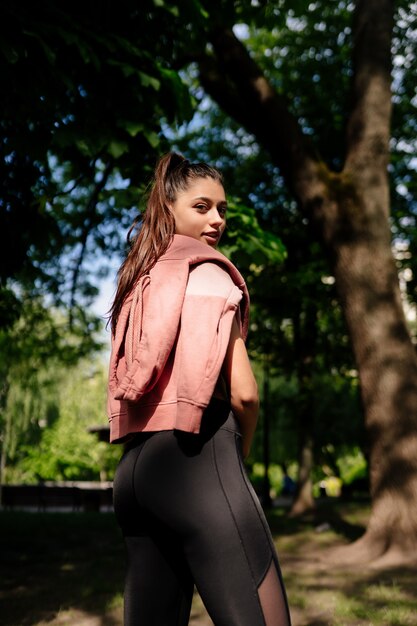 La bella giovane donna sta riposando dopo aver fatto jogging nel parco.