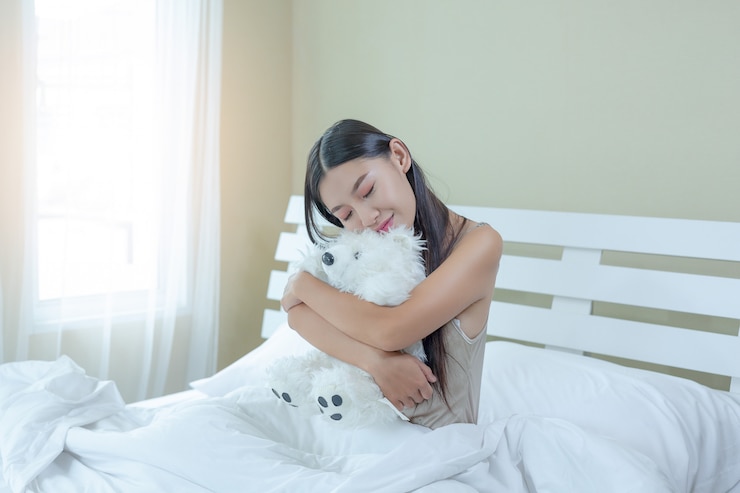 無料Photo 美しい若い女性が寝ており、自宅の寝室に目覚まし時計があります。