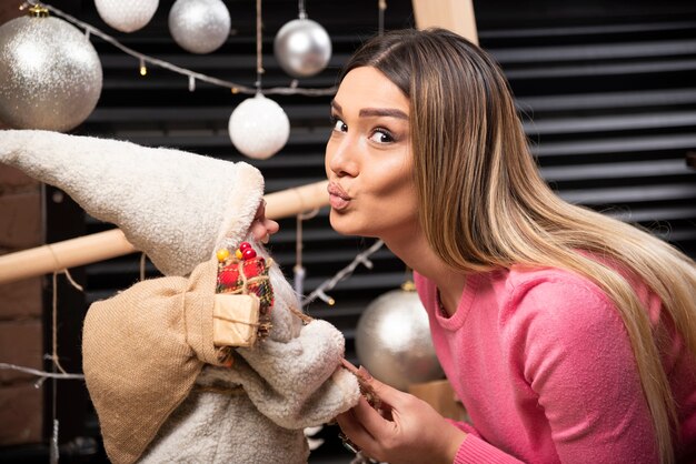 Beautiful young woman kissing doll at home.