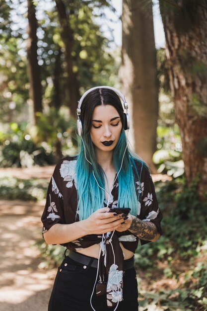 Beautiful young woman listening music on headphone through cell phone