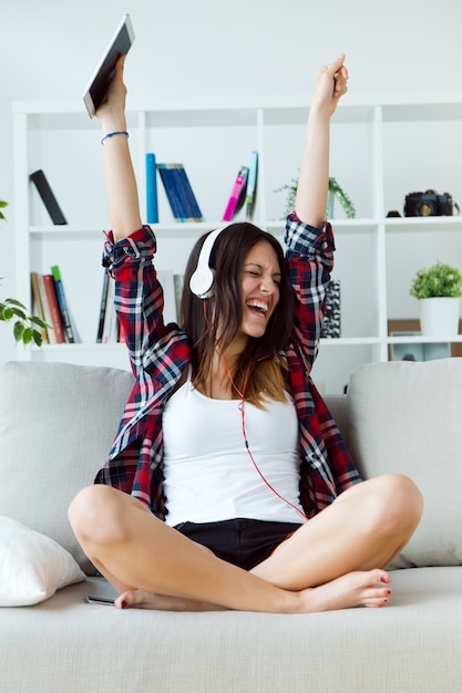 Beautiful young woman listening to music at home.