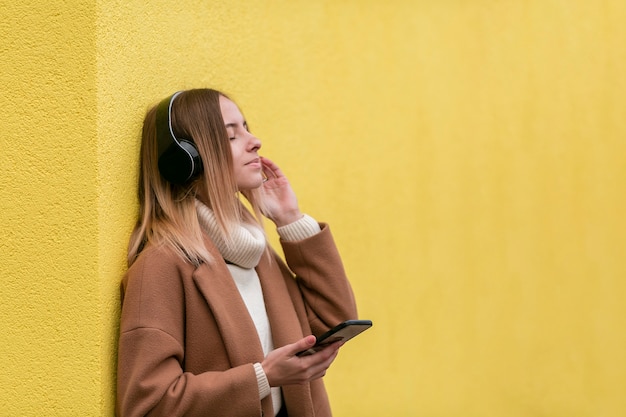 Бесплатное фото Красивая молодая женщина слушает музыку в наушниках с копией пространства