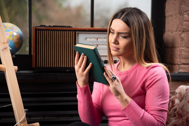 Beautiful young woman looking at book at home