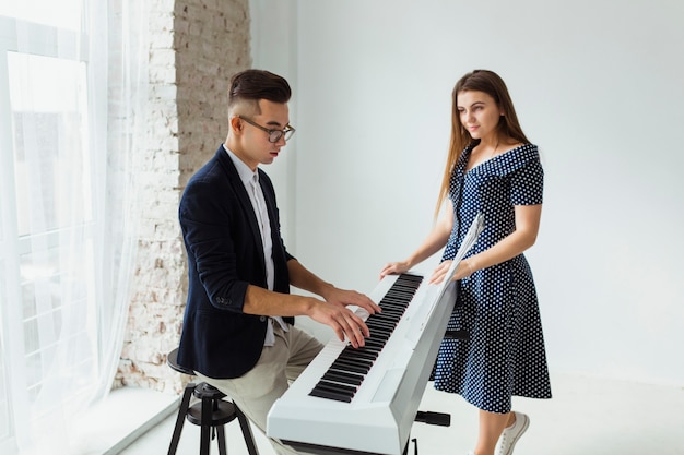 Free photo beautiful young woman looking at man playing the piano at home