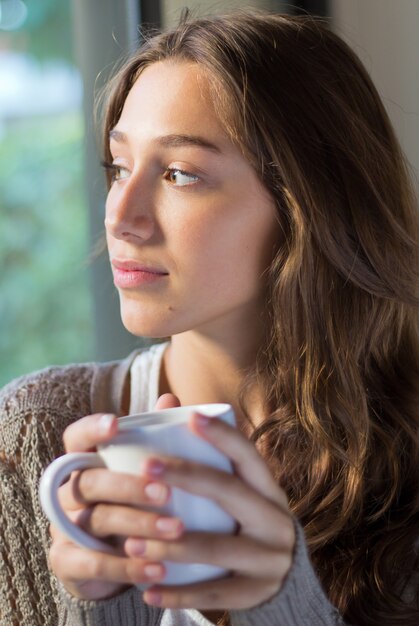 Beautiful young woman looking throught the window