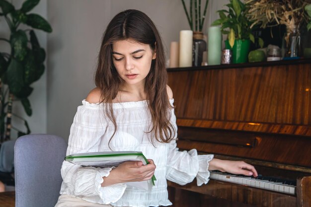 Una bella giovane donna guarda le note mentre è seduta vicino al pianoforte