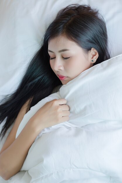 Beautiful young woman lying down in the bed and sleeping.