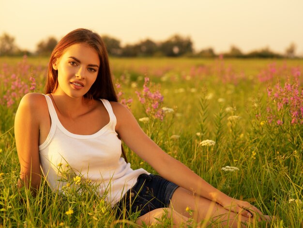 Beautiful young woman on nature over summer field background.