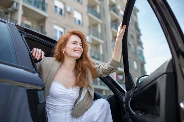 Красивая молодая женщина открывает дверь машины Привлекательная женщина выходит из машины