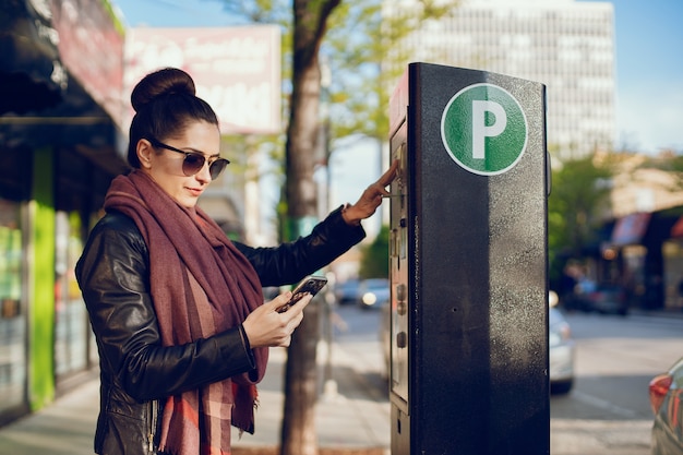 Красивая молодая женщина платит за парковку в метро на улице
