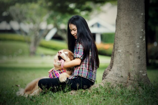 屋外の公園で彼女の小さな犬と遊ぶ美しい若い女性。ライフスタイルの肖像画。