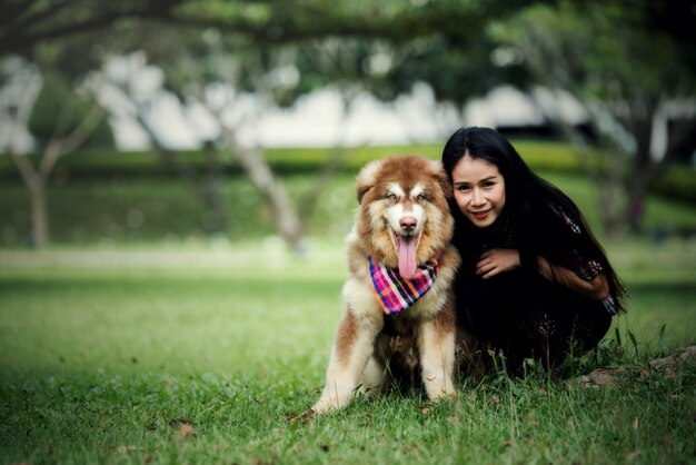 屋外の公園で彼女の小さな犬と遊ぶ美しい若い女性。ライフスタイルの肖像画。