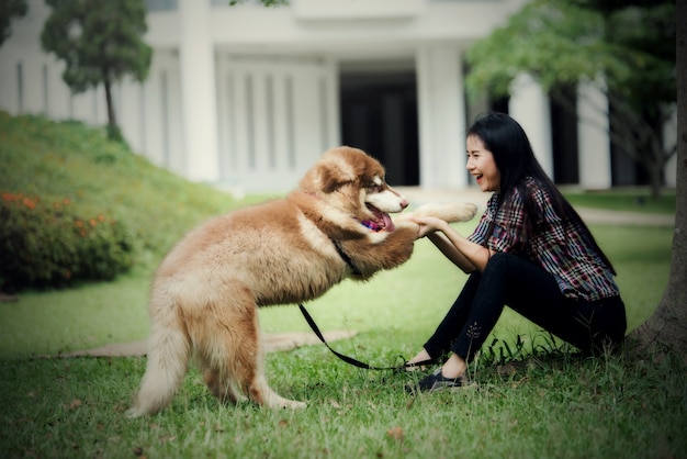 Beautiful young woman playing with her little dog in a park outdoors. Lifestyle portrait.