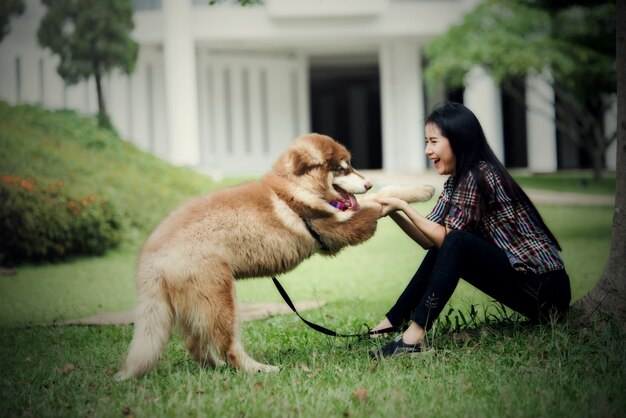 屋外の公園で彼女の小さな犬と遊ぶ美しい若い女性。ライフスタイルの肖像画。